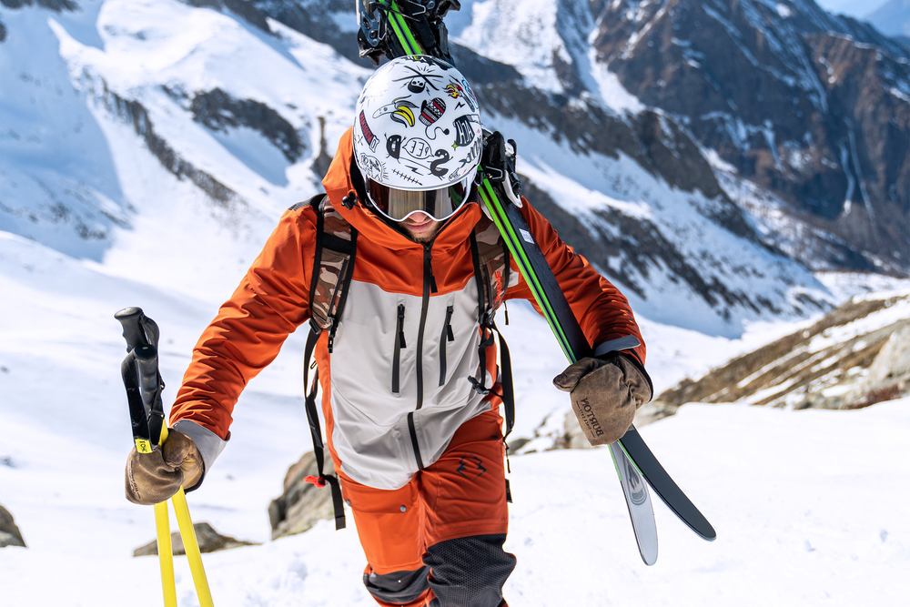 A skier hikes up a mountain through the snow with skis over their shoulder.